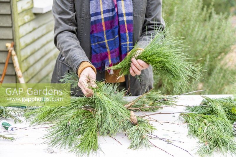 Woman placing pine sprigs over the twigs