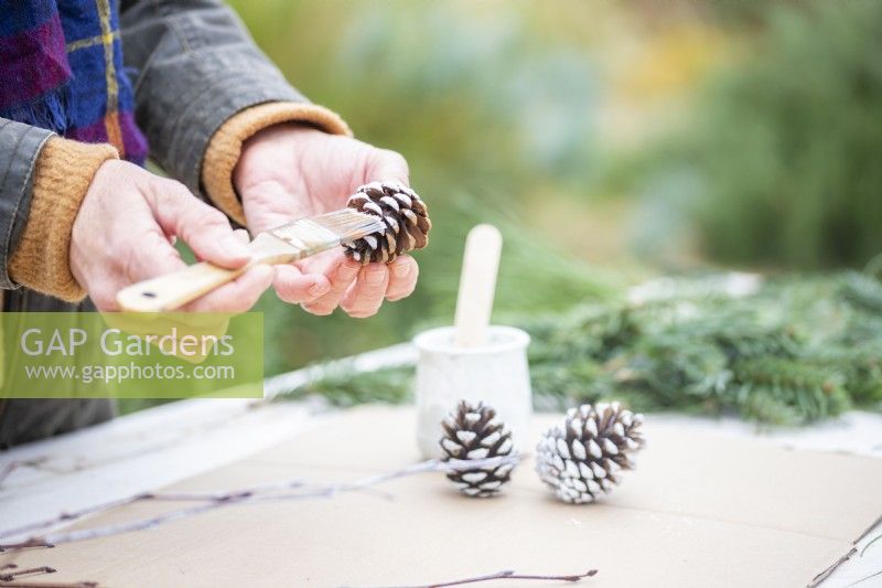 Woman painting pine cones white