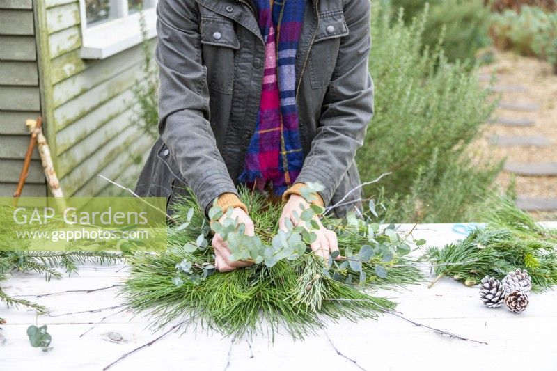 Woman placing Eucalyptus sprigs with other foliage