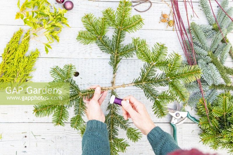 Woman wiring two pine sprigs together