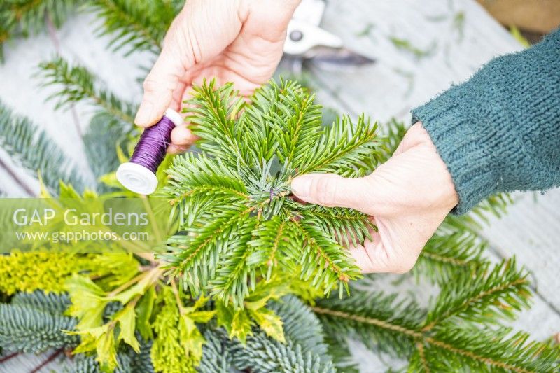 Woman wiring pine sprigs together