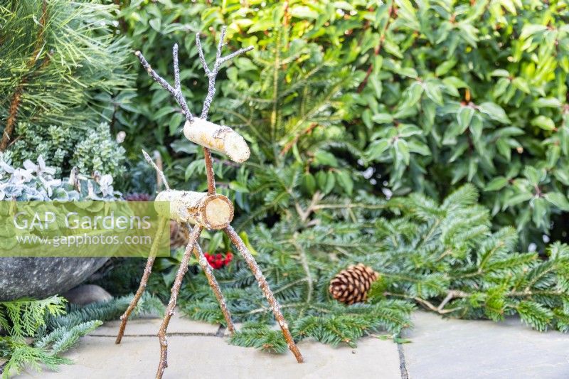 Birch reindeer next to winter container and evergreen foliage