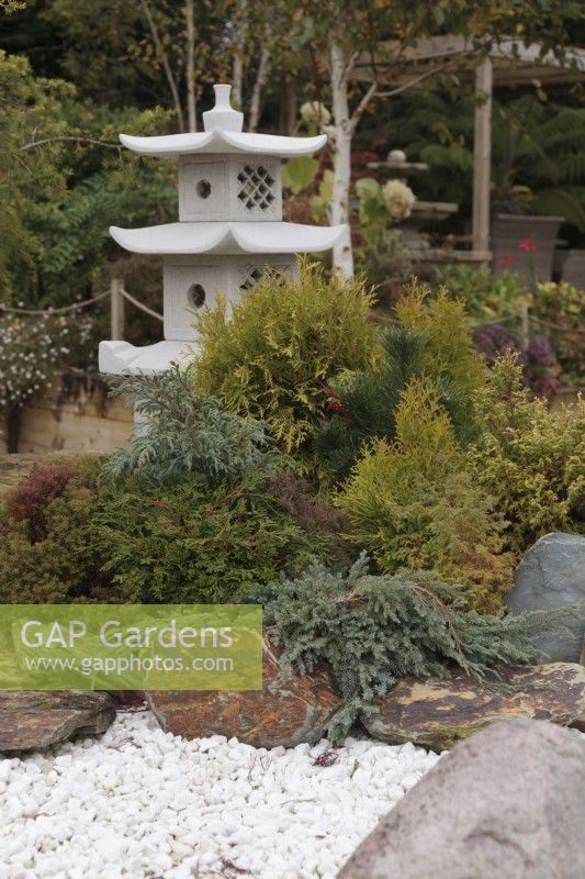 Japanese pagoda lantern surrounded by conifers, rocks and white gravel