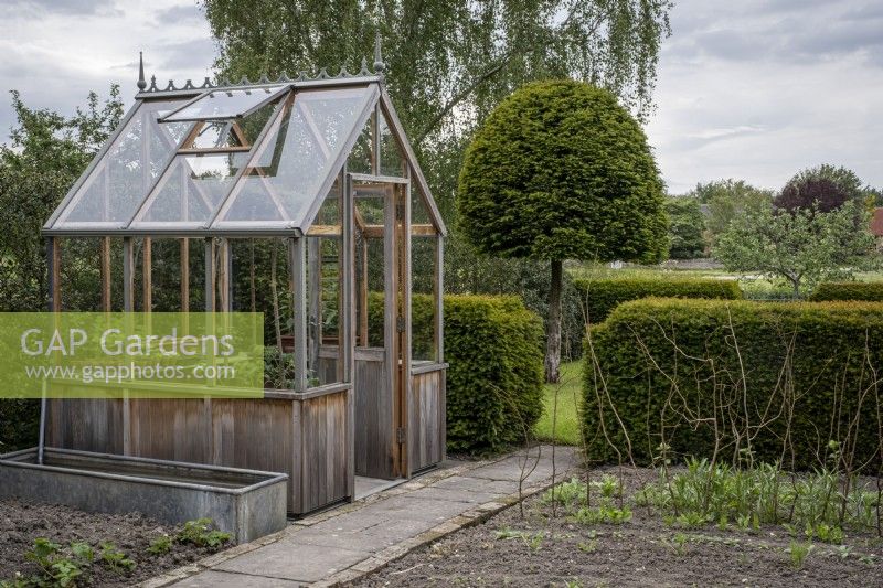 Small wooden greenhouse in cottage garden