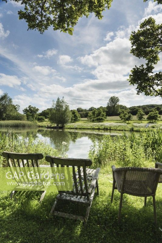 Seats beside a lake with surrounding meadows at Am Brook Meadow in June