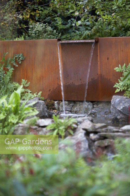 The Yeo Valley Organic Garden. Designer: Tom Massey.  Waterfall water feature made from Corten steel. Chelsea Flower Show 2021