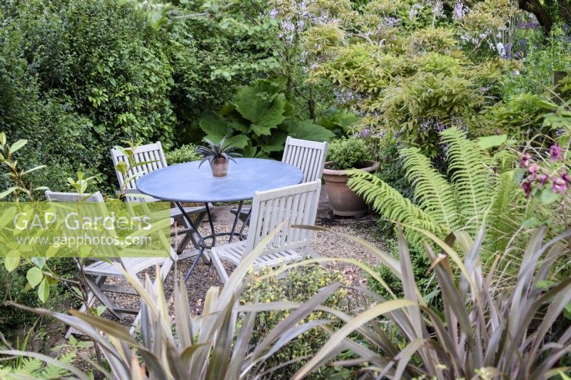Seating area surrounded by lush foliage in a June garden