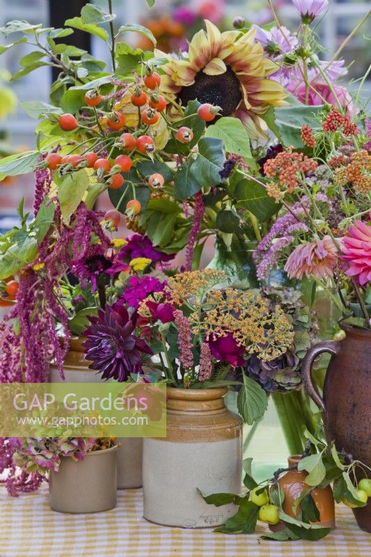 Flower arrangement on the table with dahlias, sunflowers, cosmos, sedums, amaranthus and rose hips.