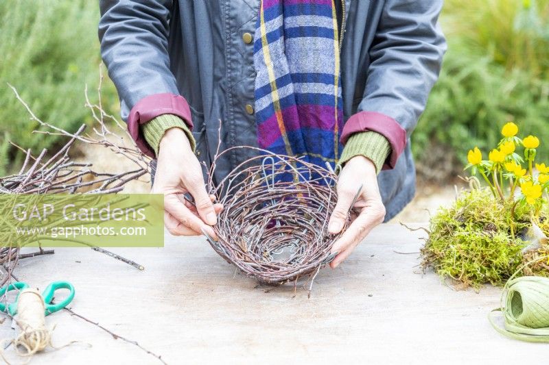 Woman weaving birch twigs through the wire frame
