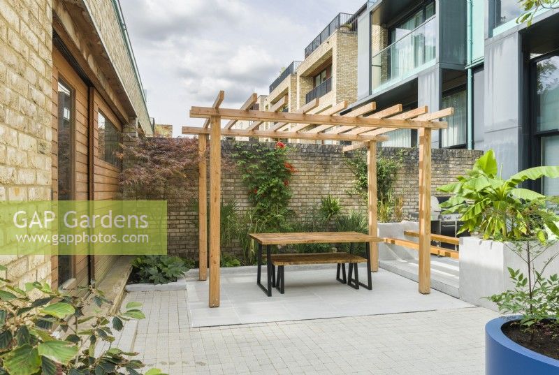 View of a contemporary courtyard garden with pergola, seating. September