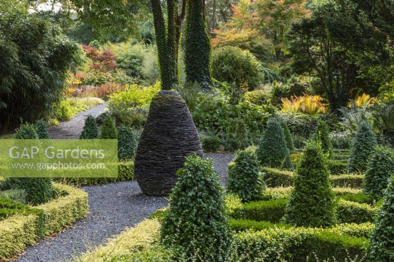 View through the formal parterre in the Slate Garden, past the sculpture of a fir cone made by Joe Smith, and towards the Rockery.