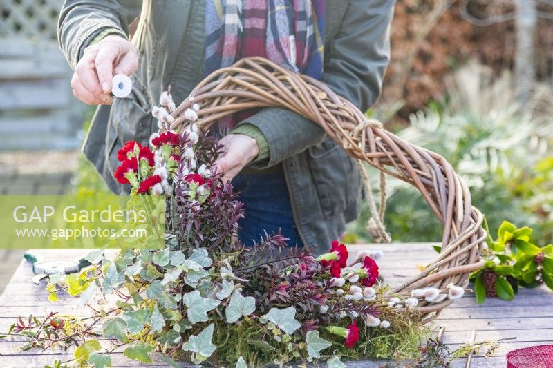 Woman using wire to tie carnations to the wreath