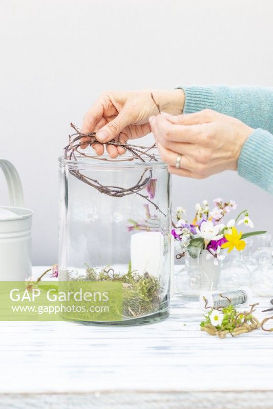 Woman placing birch twigs in the large glass container