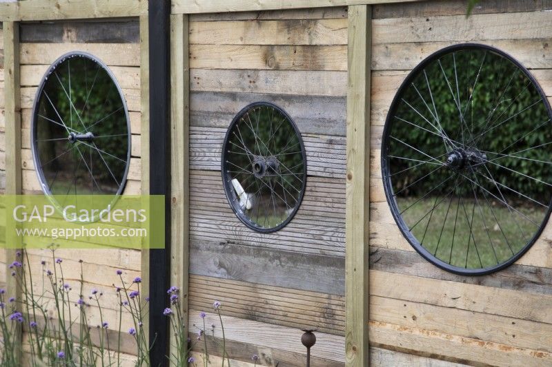 'On Your Bike!' at BBC Gardener's World Live 2021 - fence panels with bicycle wheels as cut out shapes in a cycling themed garden