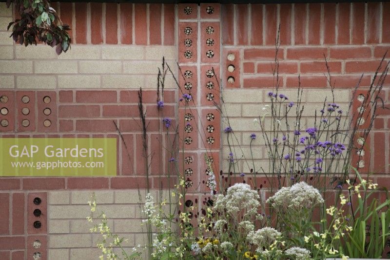 'The Marshalls Garden' at BBC Gardener's World Live 2021 - decorative brick wall with in built insect hotels, bordered by perennials