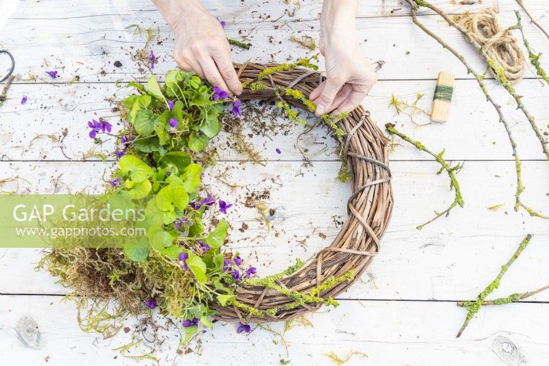 Woman placing lichen covered twigs on the wreath