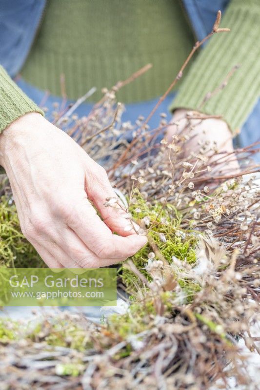 Woman placing dried seed heads on the wreath