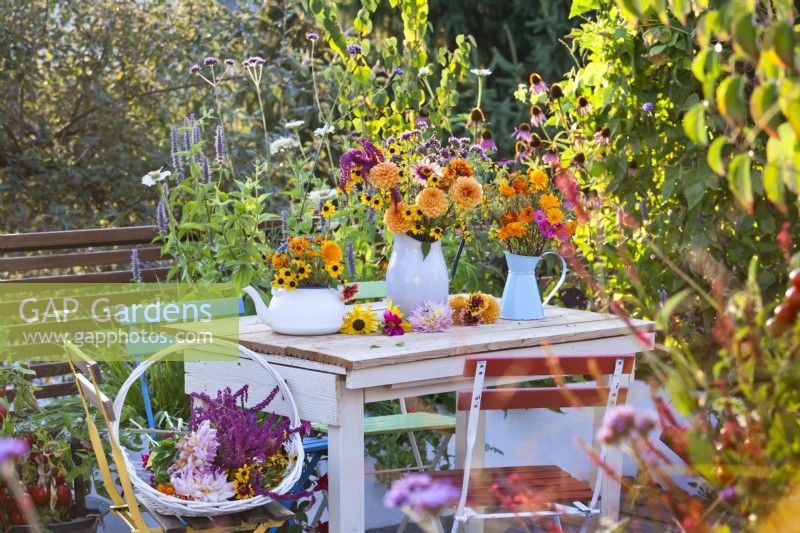 Table display with summer flower bouquets with dahlia, zinnia, rudbeckia, verbena, and calendula in vases.