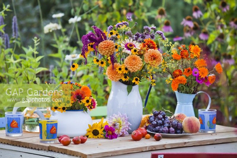 Table display with summer flower bouquets with dahlia, zinnia, rudbeckia, verbena, and calendula in vases.