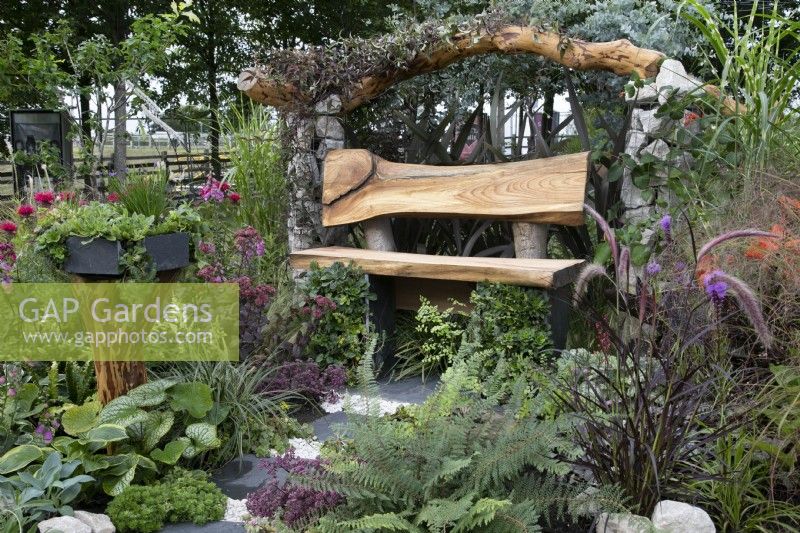 'Health and Relaxation Border' at BBC Gardener's World Live 2021 - rustic bench amongst the annuals and vegetables