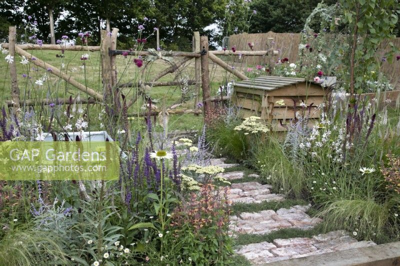 'The Earth Smiles with Flowers' at BBC Gardener's World Live 2021 - cottage garden with rustic brick and camomile path, beehive and muted perennial planting