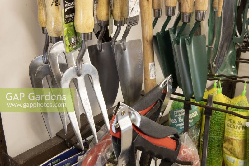 A variety of garden tools for sale in a garden centre including forks and trowels. 