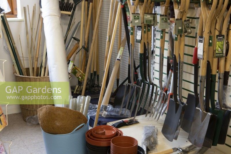 A variety of tools, plant pots and other gardening sundries in a garden centre shop. Forks, spades, hoes, tree guards. 