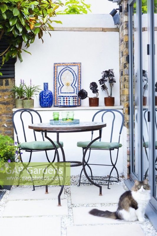 Mediterranean corner with table and chairs and small Moroccan tile fountain. 