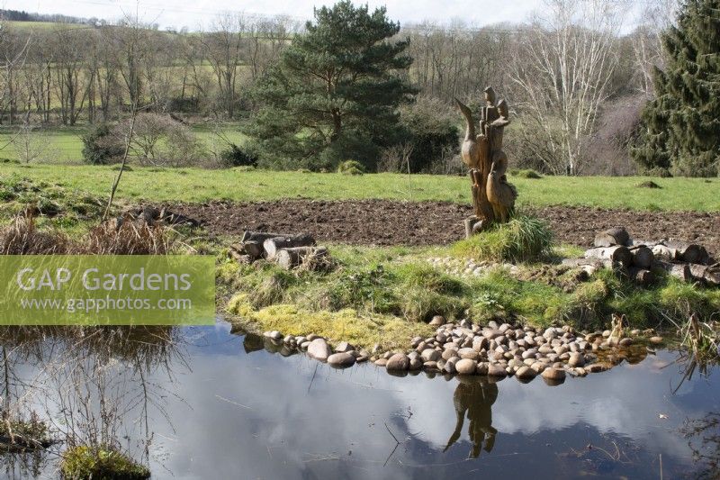Wooden carved bird statue next to the wildlife pond in John's Garden at Ashwood Nurseries - Kingswinford - Spring