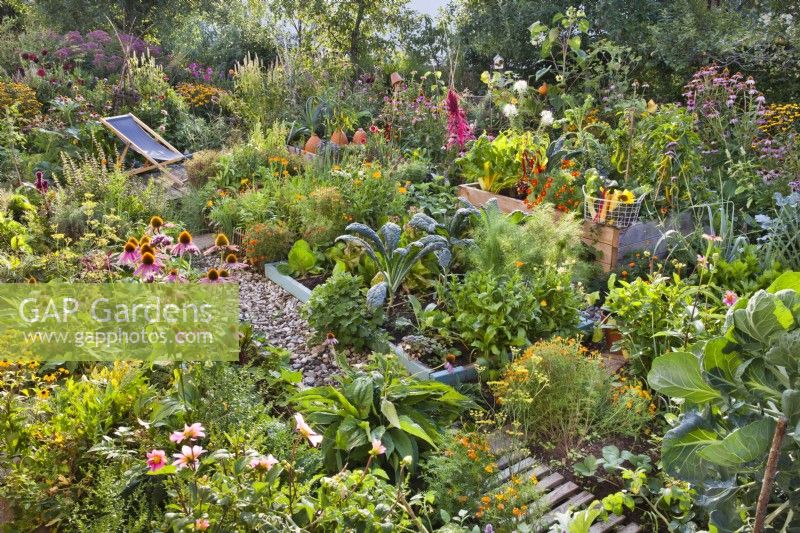 Organic kitchen garden with raised beds and small patio with a deckchair.