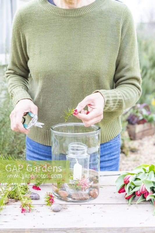 Woman placing grevillea sprigs in the large glass container