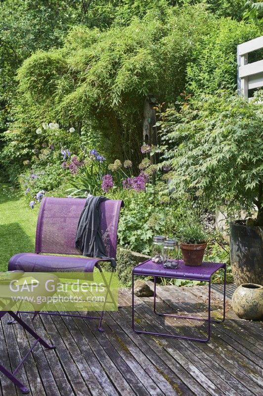 Purple furniture on wooden decking, view to garden behind