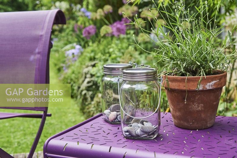 Lavendula angustifolia, glass jars lantern with solar lamp from Sonnenglas on side table from Fermob and a lavender in a clay pot