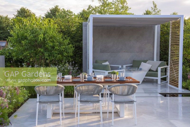 Outdoor dining area  with metal pergola and seating under.  Lower Barn Farm: The Bounce Back Garden, RHS Hampton Court Palace Garden Festival 2021