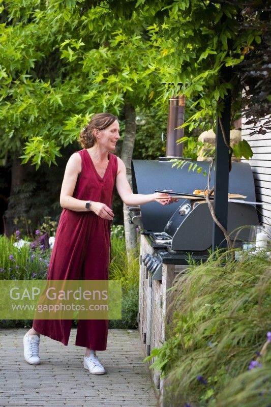 Lisa, garden owner baking pizza in the outdoor pizza oven. 