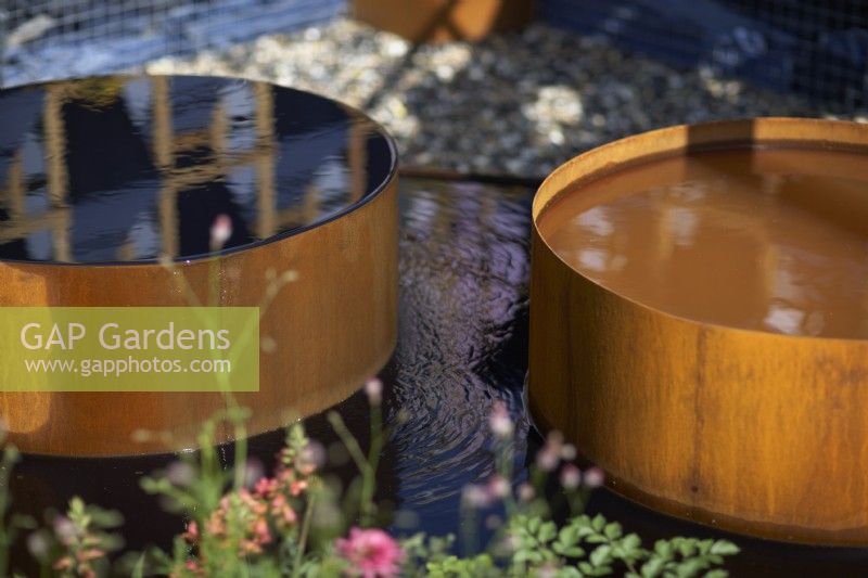 The Fashion Footprint Garden. Designer: Baz Grainger. A water feature made of corten steel. RHS Hampton Court Palace Garden Festival Show 2021