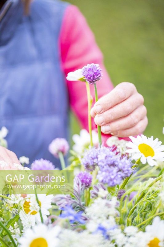 Woman placing Chive in wildflower bouquet