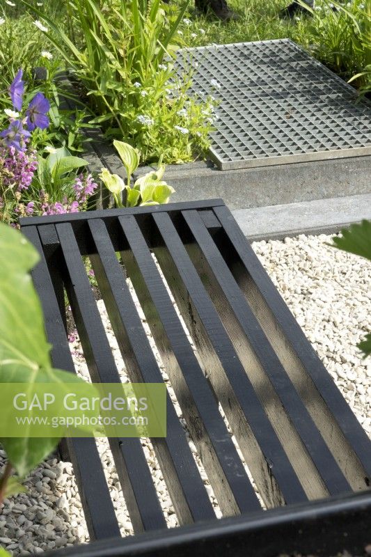 Black bench and small pond covered with metal grid.
