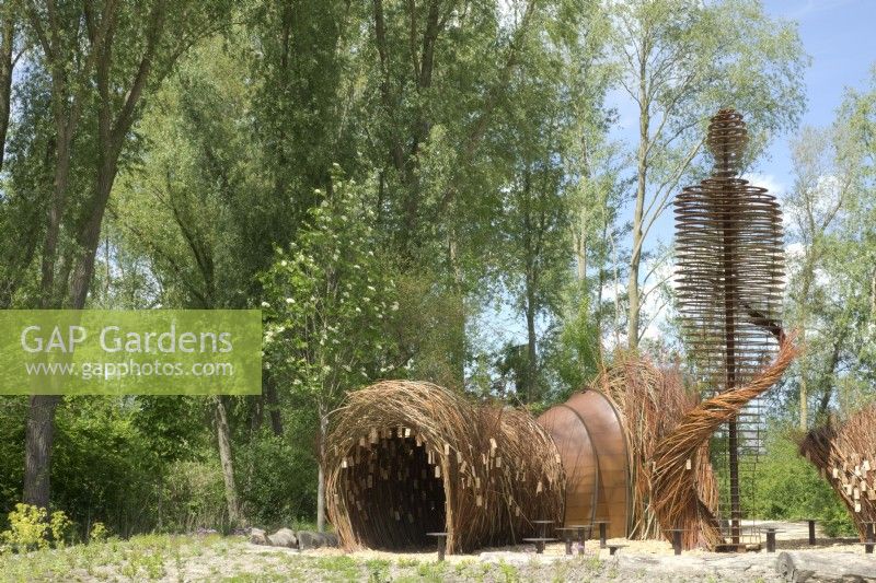 Arch of willow branches and corten steel human statue as landart designed by Will Beckers.