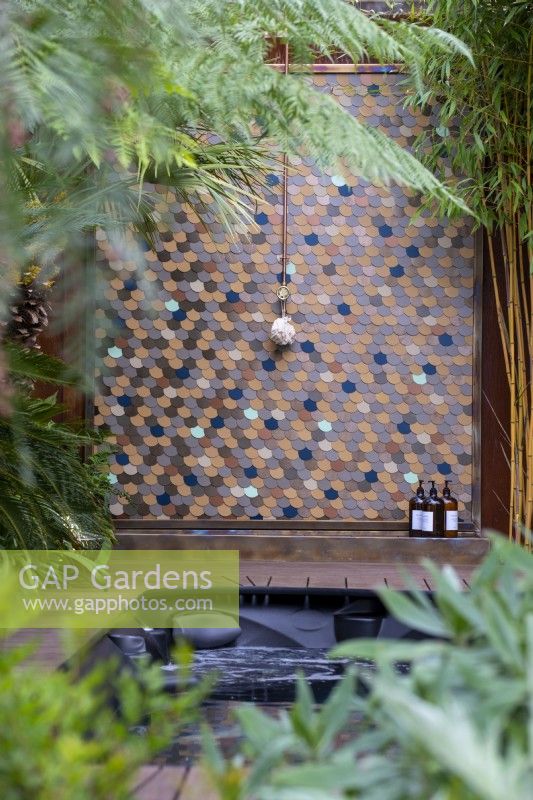 View through lush green planting to outdoor copper shower and swim spa - Out of the Shadows, RHS Chelsea Flower Show 2022 - Gold Medal