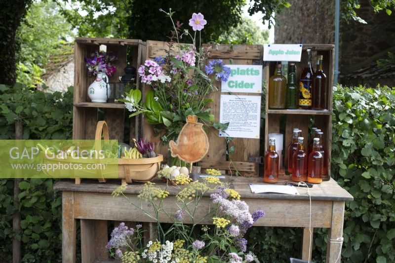 An English village flowershow competition display of garden produce including flowers, vegetables, homemade apple juice and cider.