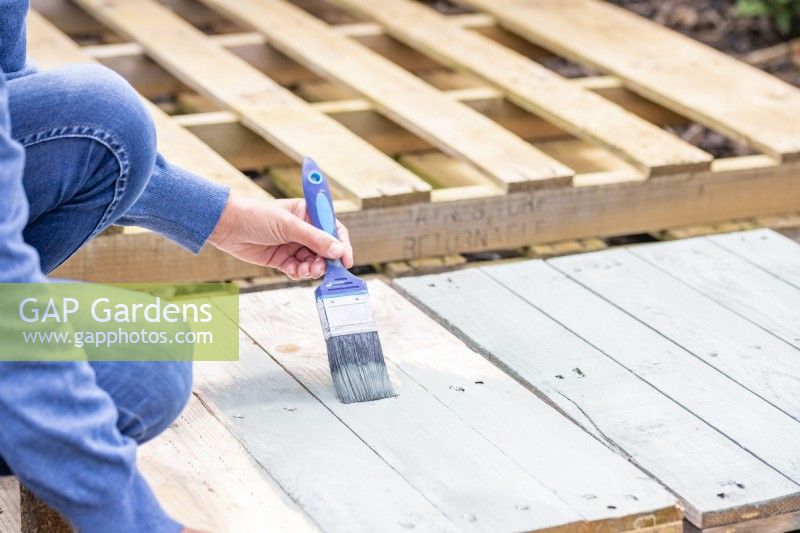 Woman painting the pallets and wooden planks