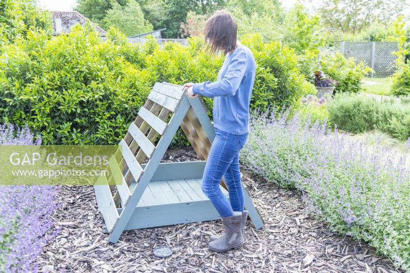 Woman screwing the two leaning pallets together
