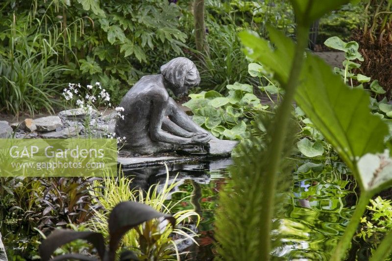 Bronze female sculpture sitting at the edge of the pond at Hamilton House garden in May 