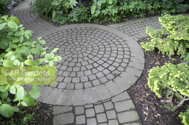 Granite sett circle with three paths leading off at Hamilton House garden in May 