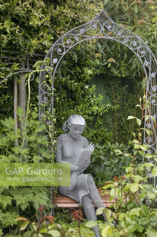 Wire sculpture of a girl reading a book by Derek Kinzett at Hamilton House garden in May 