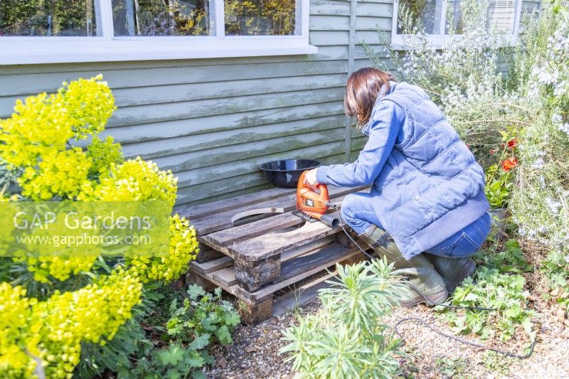 Woman cutting a hole out of the pallet one centimetre in from the line