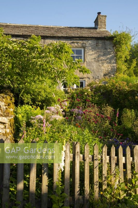 A wooden fence and herbaceous borders in front of the White House in Countersett, Yorkshire
