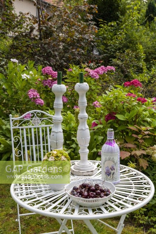 Table decoration with bottle lamp in front of a hydrangea bed