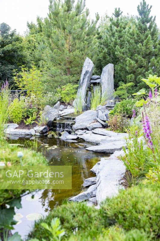 Natural large stone waterfall feature at the end of a pond